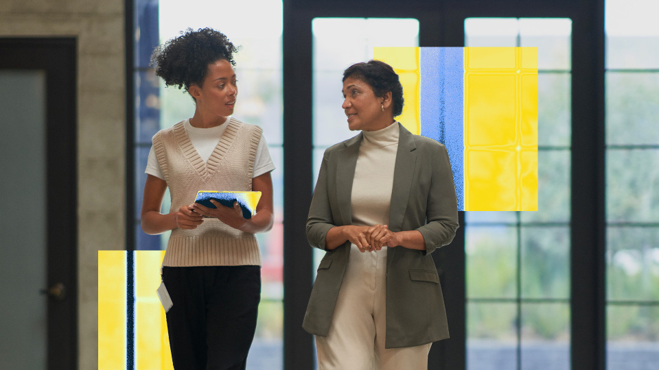 Two people walk through the lobby of an office building.