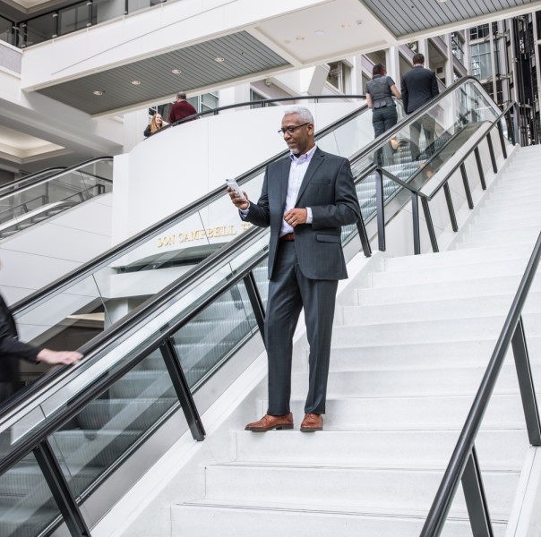 Person standing on stairs, looking at a phone in their hand