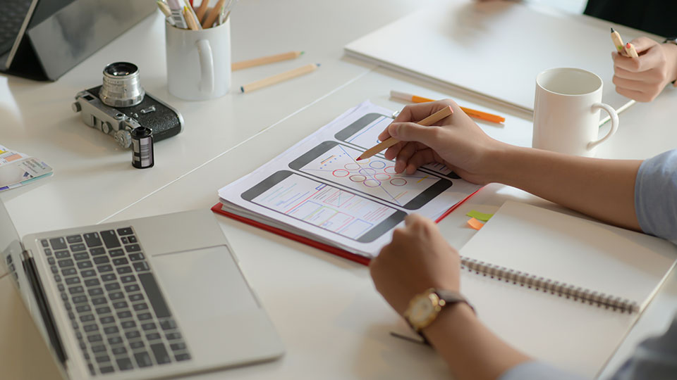 A man works on a mobile wireframe document at a desk