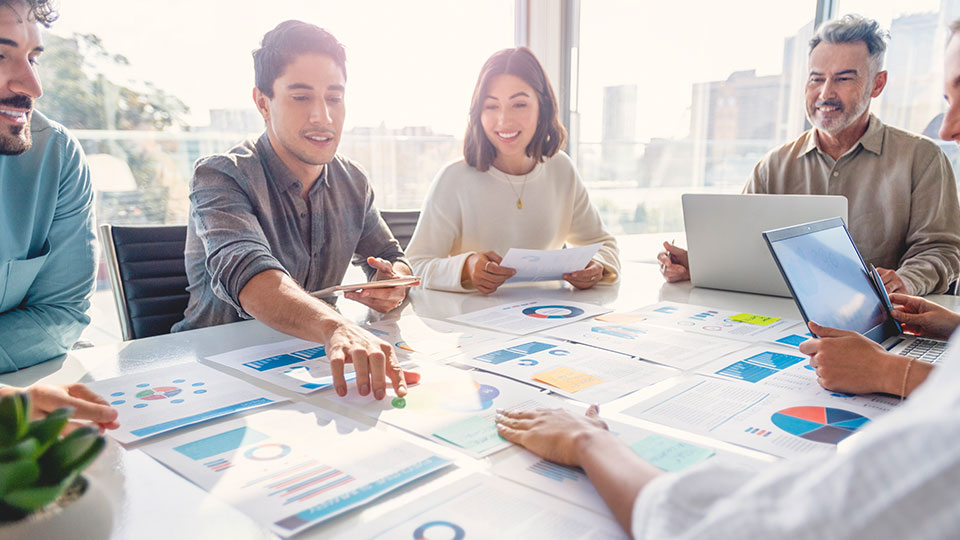 A group of coworkers look at documents spread out on a conference table