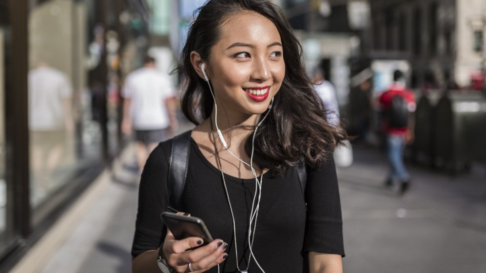 Young woman speaks into phone on city street