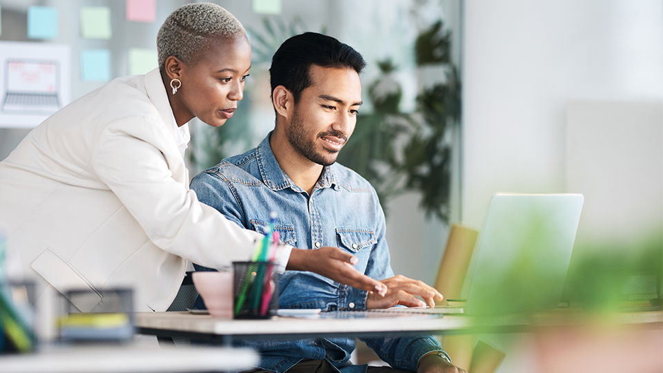 Woman advising a man who is working on a computer