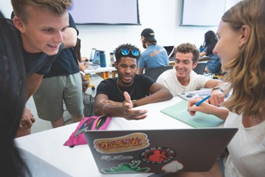 Students looking at a laptop in a classroom.