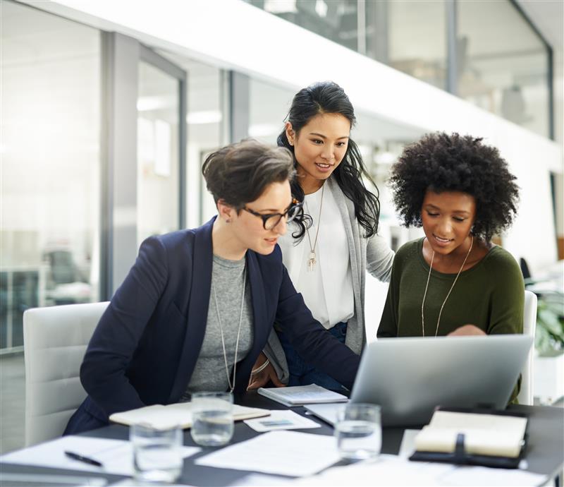 Three women working at a desk with a computer.