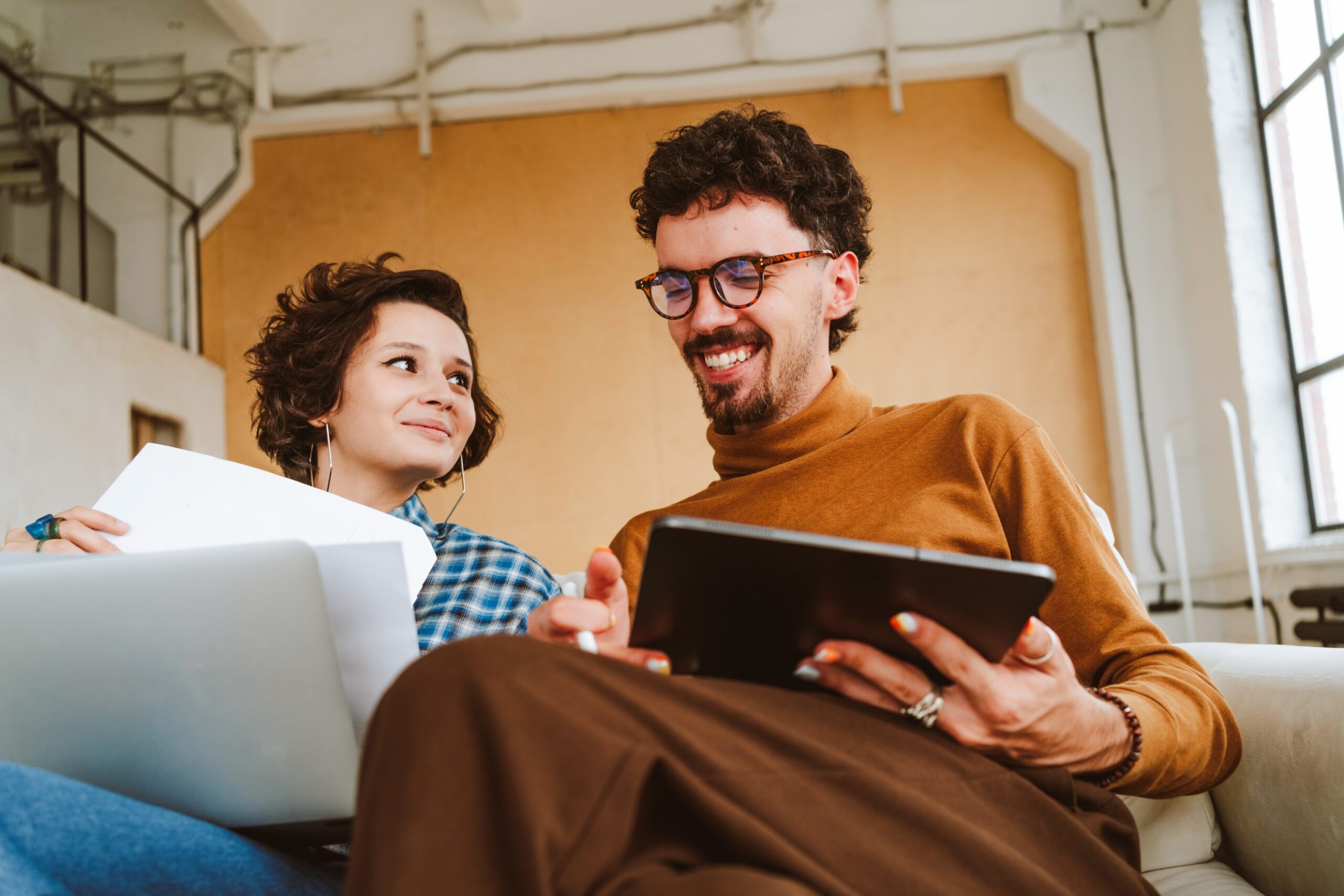 Two people smiling with a tablet and paper