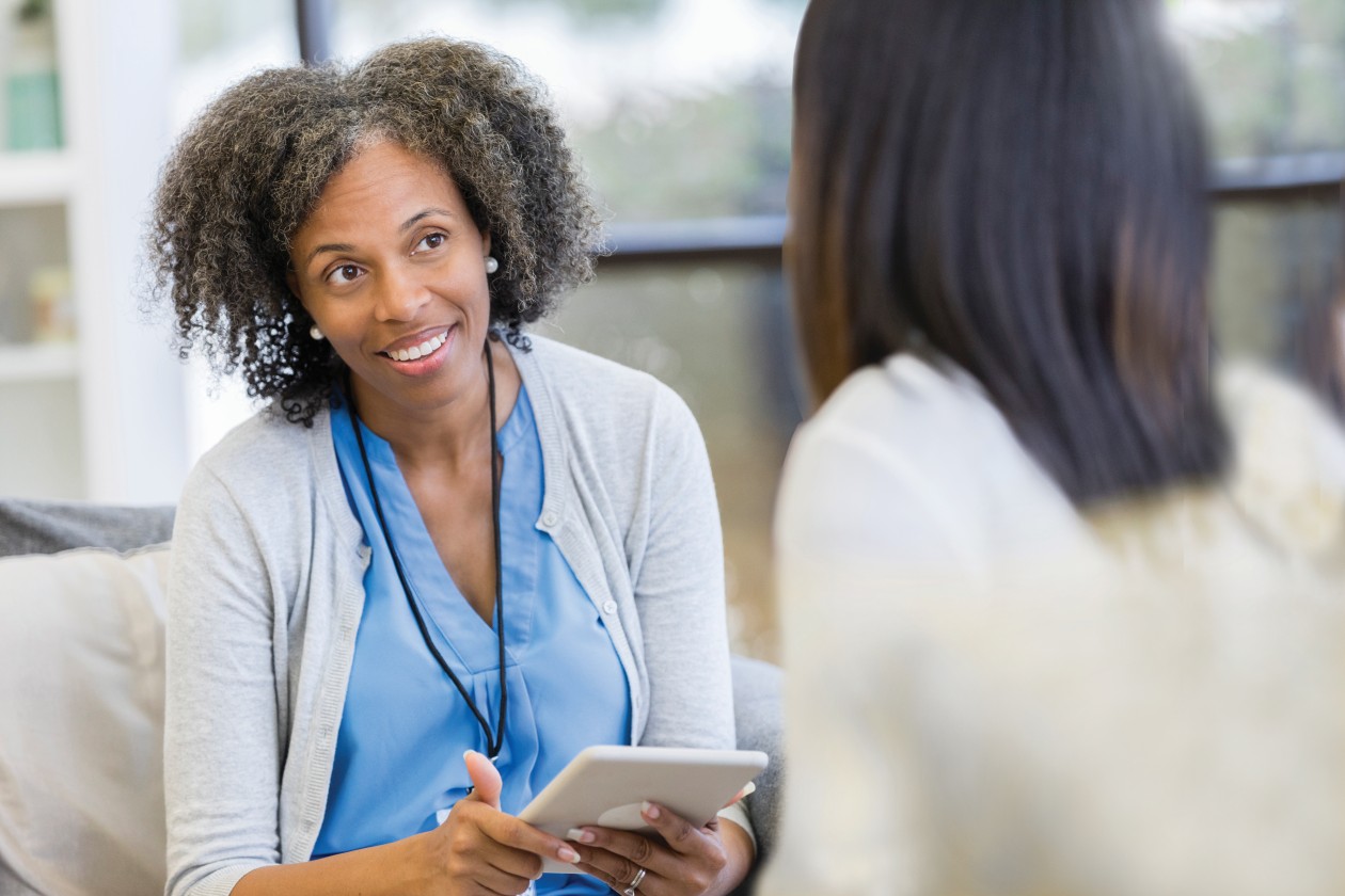 Female doctor talking with patient holding tablet.