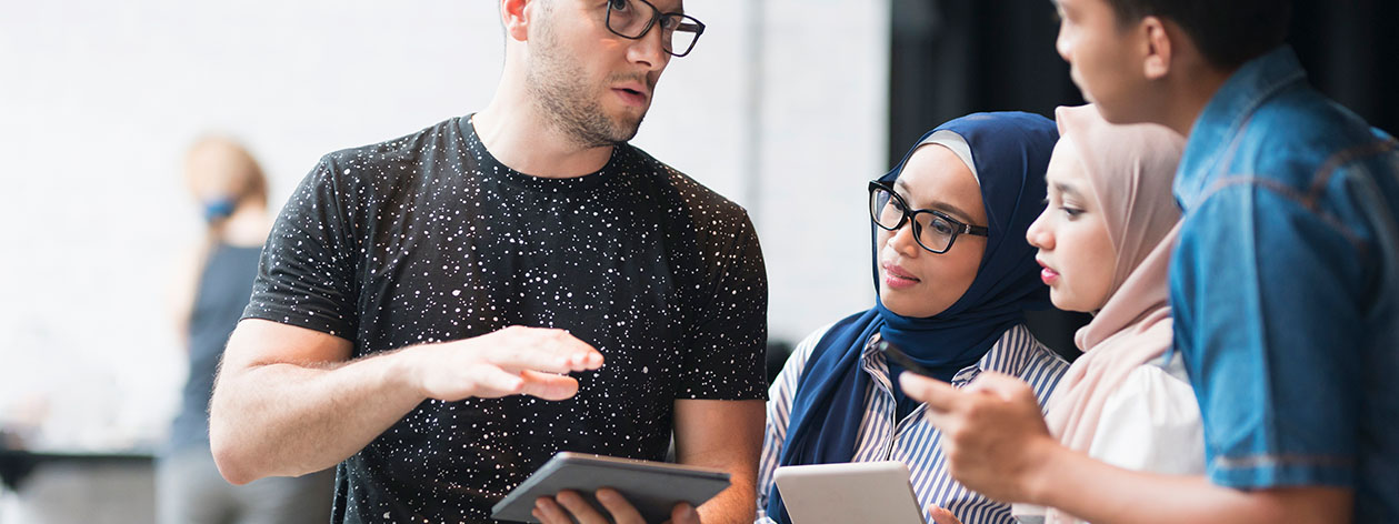 Um professor apontando para uma tela projetada em uma sala de aula