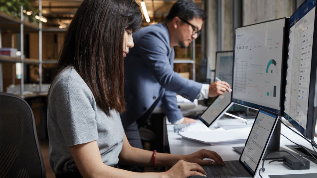 Two people work at their PCs in an office.
