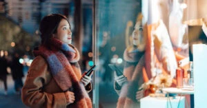 夜のウィンドウショッピングをスマホ片手に楽しむ女性