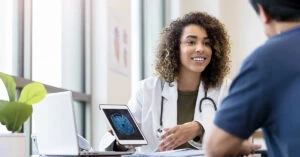 タブレットを片手に患者に検査画像を説明する女性医師