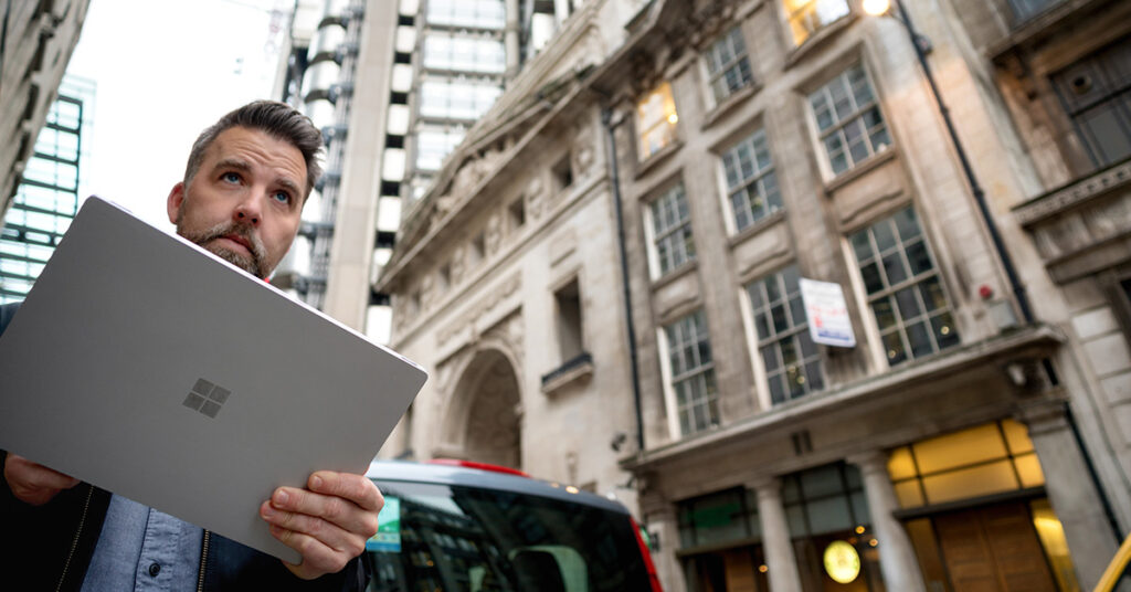 ロンドンのあるビル前にてSurfaceを持ちながら道の先を見つめる男性