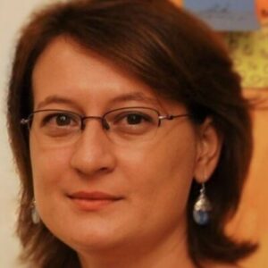 a woman wearing glasses and smiling at the camera