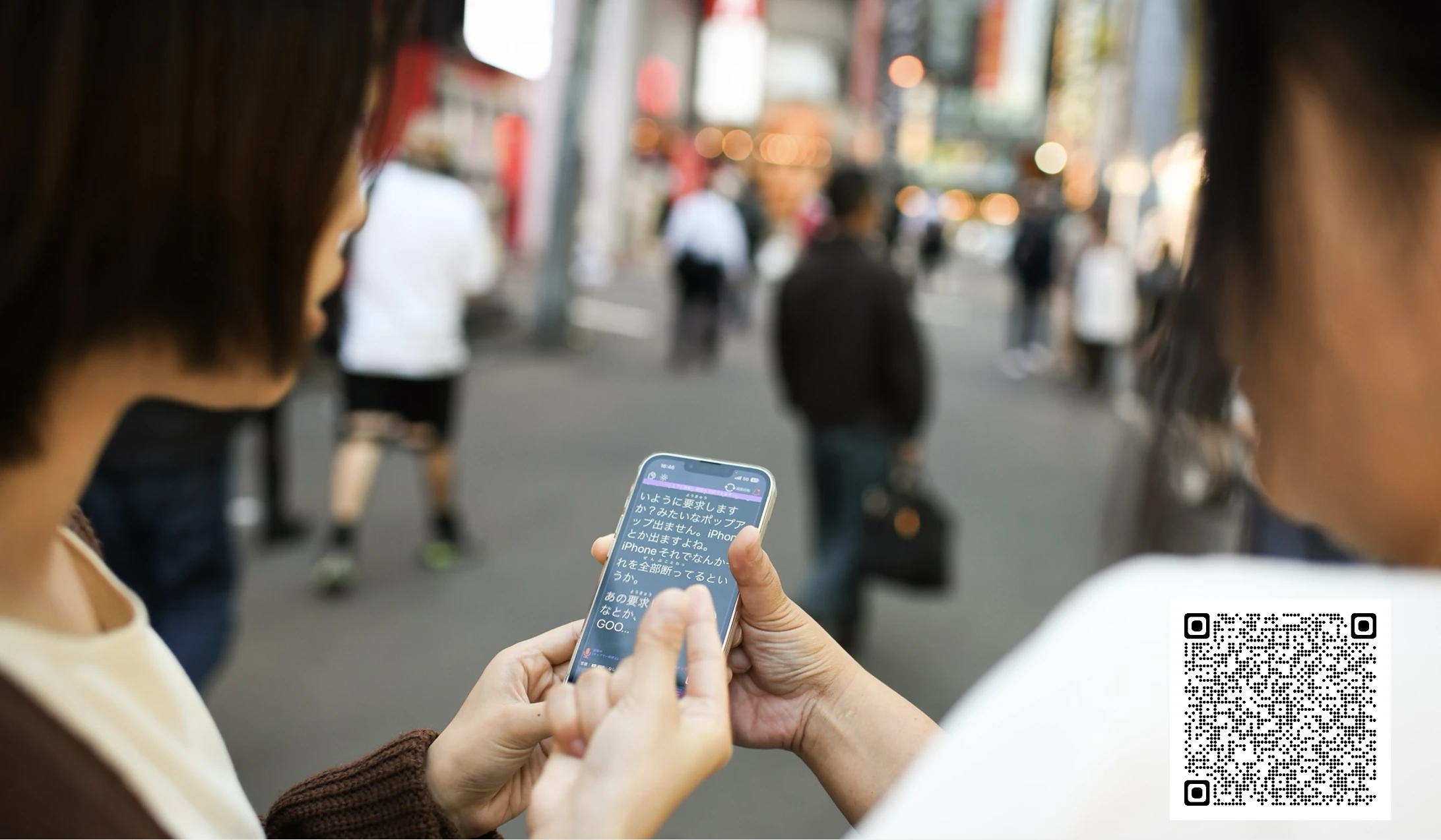 1 つのスマートフォンを覗き込む 2 人の女性
