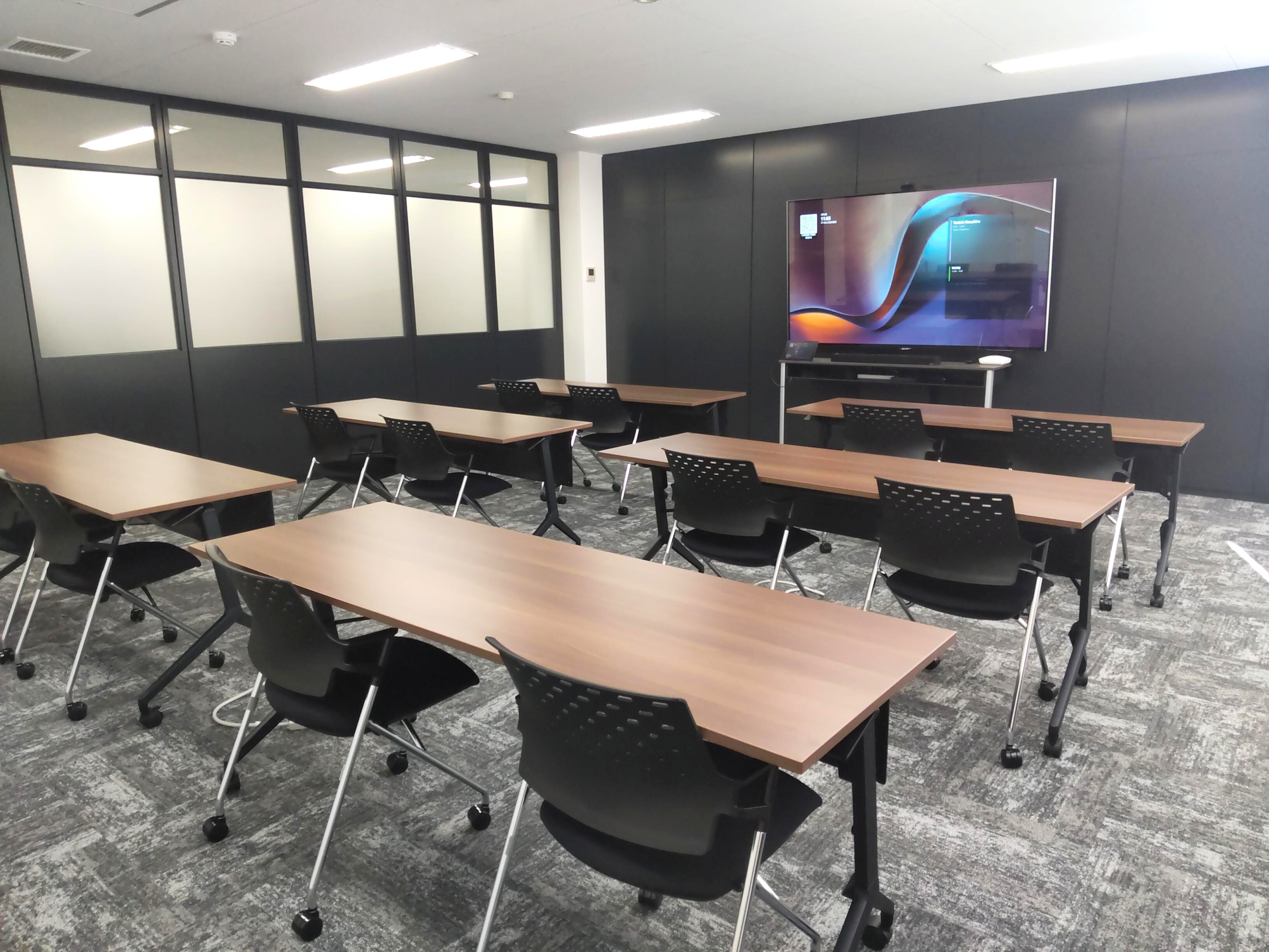 大型モニターに向かって列になった机が並ぶ研修室。