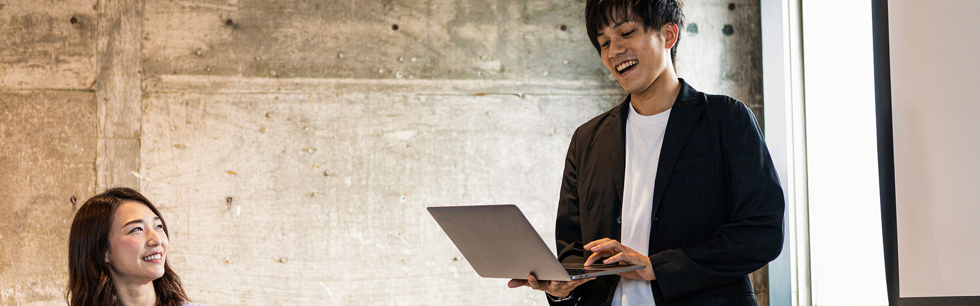 プレゼンテーションをしながらノートパソコンを見るビジネスマン