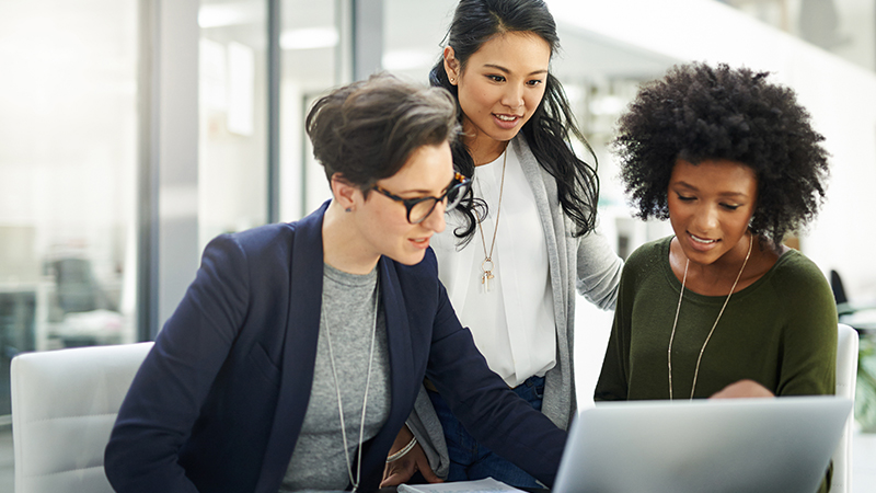 Grupo de empresárias usando um laptop durante uma reunião no trabalho.