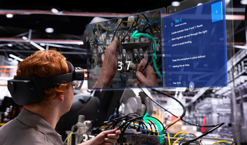 Um homem usa um dispositovo Hololens para criar uma tela virtual em uma fábrica.